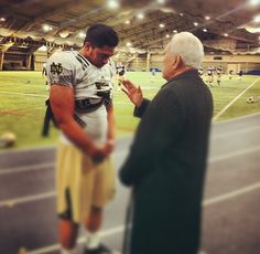 an old man is talking to a football player