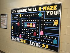 a bulletin board on the wall in a school hallway with pacman and ghostbus