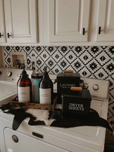 a white washer sitting inside of a bathroom next to a bottle of wine and soap