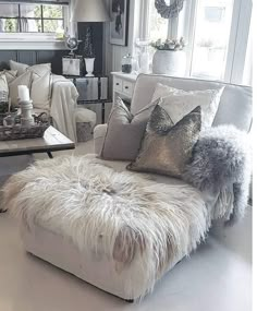 a living room filled with white furniture and lots of pillows on top of it's back