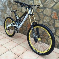 a bike parked next to a stone wall with yellow and black rims on it