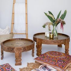 two wooden tables sitting next to each other on top of a floor covered in rugs