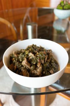 a white bowl filled with food on top of a glass table