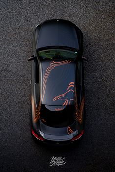 an overhead view of a black sports car with flames painted on it's hood