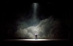 a man standing in the middle of a dark room with light coming from behind him