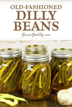 three jars filled with pickles and onions on top of a wooden table next to garlic