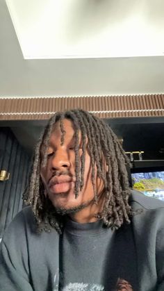 a man with dreadlocks sitting in front of a tv