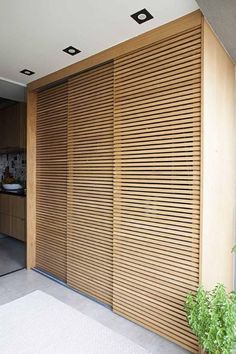 an open sliding door with wooden slats on the side and plants growing in front