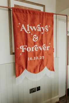 an orange banner hanging on the wall in front of a door with words always and forever