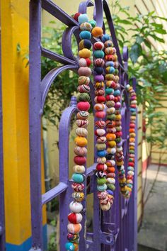 a bunch of beads hanging from a purple fence