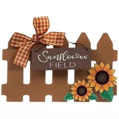 a wooden sign that says sunflower field with two sunflowers on the fence