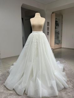 a white wedding dress on display in a room with mannequins behind it