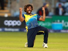 a man in blue and yellow uniform standing on top of a green field with his arms up