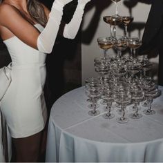 a woman in white dress pouring champagne into wine glasses