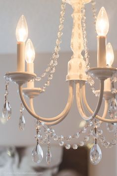 a white chandelier with crystal drops hanging from it's arms and two candles in the middle