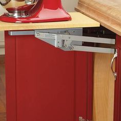 a red stand mixer on top of a wooden counter next to a kitchen island with drawers