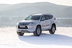 a silver suv parked in the snow near mountains