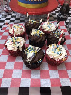 cupcakes with candles and sprinkles on a checkered tablecloth