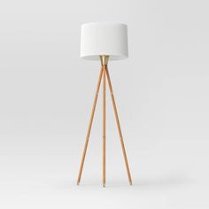 a wooden tripod floor lamp with a white shade