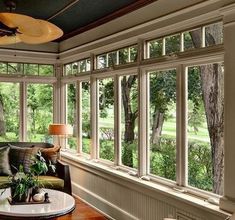 a living room filled with lots of windows next to a table and chair in front of a window