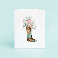 a greeting card featuring a cowboy boot with flowers in it on a blue background,