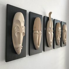 four masks are mounted on the wall next to each other in different shapes and sizes