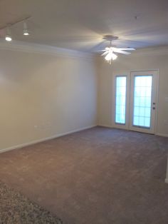 an empty living room with carpeted floors and doors