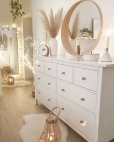 a white dresser topped with lots of drawers next to a wall mounted clock and lights