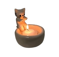 a cat candle holder with a lit candle in it