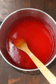 a wooden spoon sitting in a pot filled with red liquid on top of a table