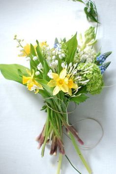 a bouquet of flowers sitting on top of a white table next to a green leafy plant