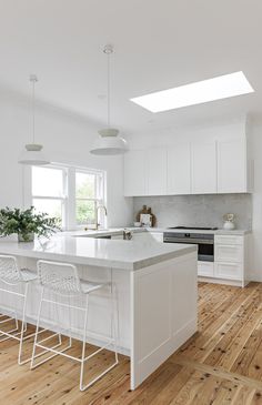 a large kitchen with white cabinets and wooden floors