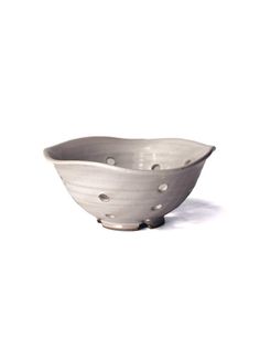 a white bowl with holes in it on a white tableclothed surface, the bowl is shaped like a boat