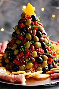 a christmas tree made out of olives and cheese on a platter with crackers