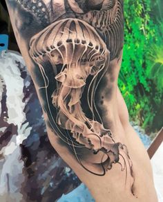 a man's leg with a tattoo on it that has a jellyfish in the water