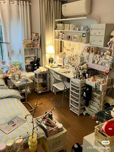 a room filled with lots of clutter next to a bed and desk in front of a window