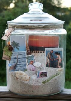 a glass jar filled with pictures sitting on top of a table