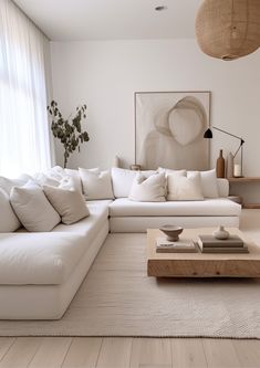 a living room with white couches and pillows on the floor in front of a large window