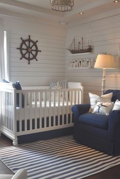 a baby's room with a blue couch, white crib and ship wheel on the wall