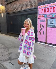 a woman walking down the street while holding a coffee cup