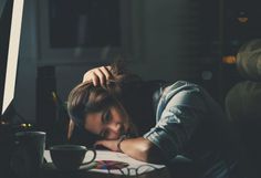 a woman sitting at a desk with her head on her hands