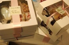 two white boxes with pink ribbons and tags on them, one is filled with cookies