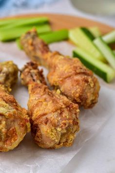 some chicken wings and celery sticks on a white paper with a wooden plate