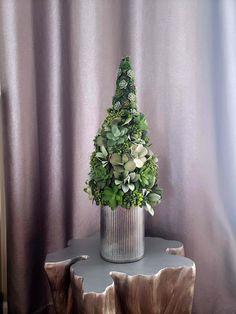 a potted plant sitting on top of a wooden table next to a purple curtain