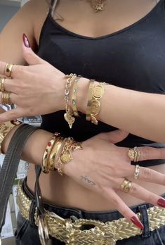 two women wearing gold rings and bracelets with their hands in each other's pockets