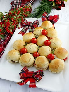 a platter filled with mini sandwiches and cherry tomatoes on top of white paper wrapped in red ribbon