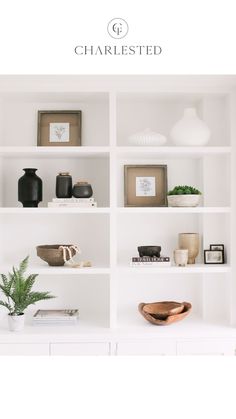 a white book shelf filled with books and vases