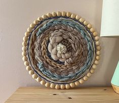 a wooden table topped with a basket filled with yarn next to a lamp and painting on the wall