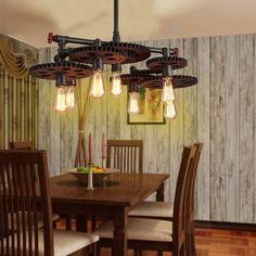 a dining room table and chairs with light bulbs hanging from the chandelier over it