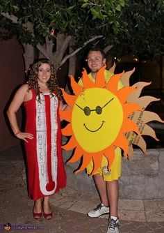 two people standing next to each other in front of a tree with a large sun on it